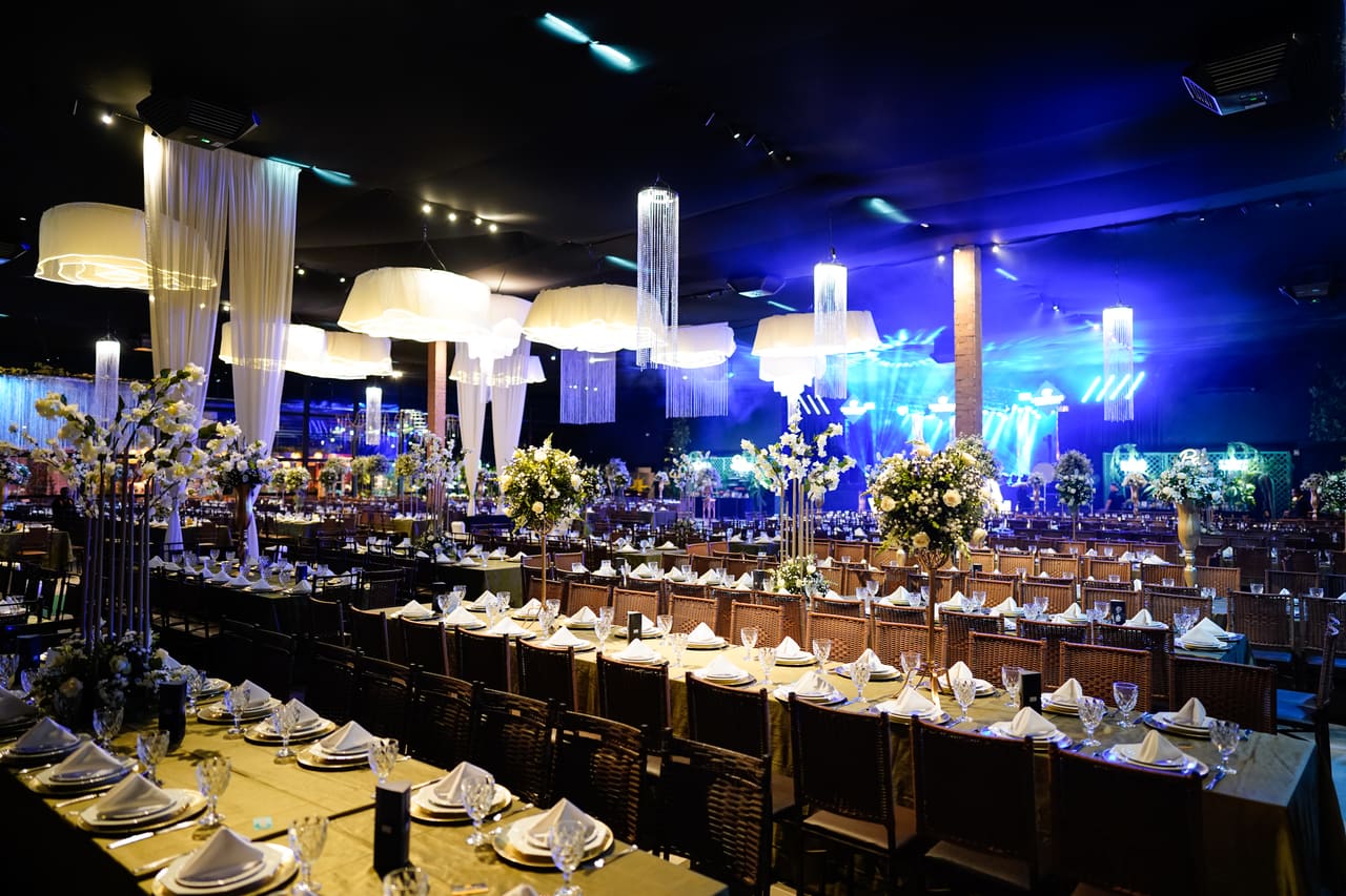 Salão de eventos decorado com lustres florais e passarela iluminada