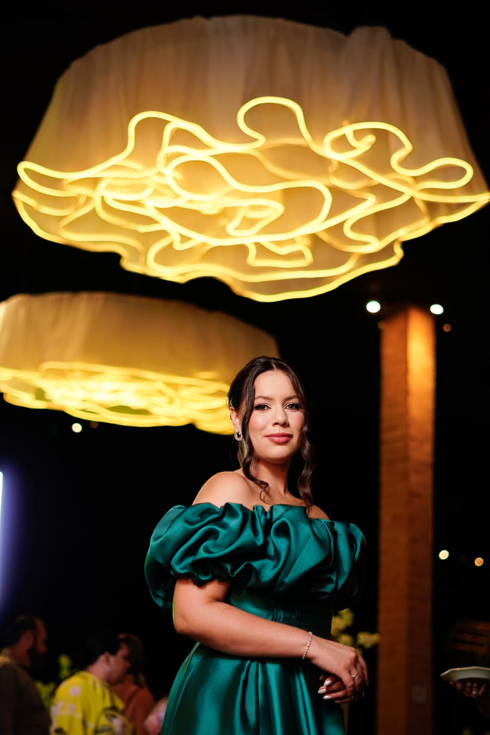 Formanda em vestido de gala sob os lustres iluminados da formatura